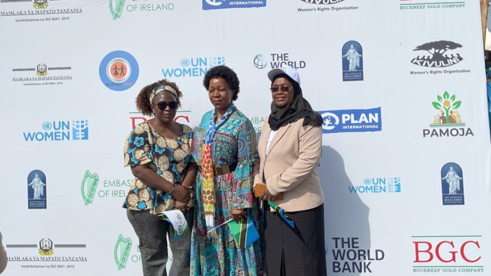 Sœur Judith Spendi, conseillère d’organisation de l’Interrégion de l’Église (au centre), pose pour une photo avec des responsables du ministère devant une bannière affichant les noms des organisations ayant soutenu le ministère dans les préparatifs des célébrations de la Journée internationale des femmes, le 8 mars 2026 à Geita, en Tanzanie.